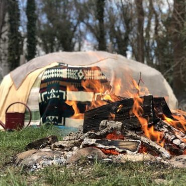 Ein brennendes Feuer vor der eingedeckten Schwitzhütte.