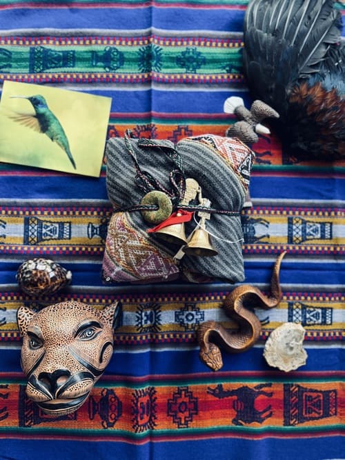 Buntes peruanisches Altartuch mit einer Schlange aus Holz, einem Jaguarkopf aus Ton, einem Bild mit einem Kolibri, einer Adlerfigur und einer Mesa in einem Mestanatuch.